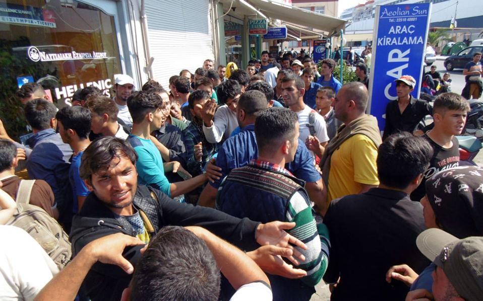 Πλήθος μεταναστών και προσφύγων έξω από εκδοτήρια εισιτηρίων στο λιμάνι της Μυτιλήνης.